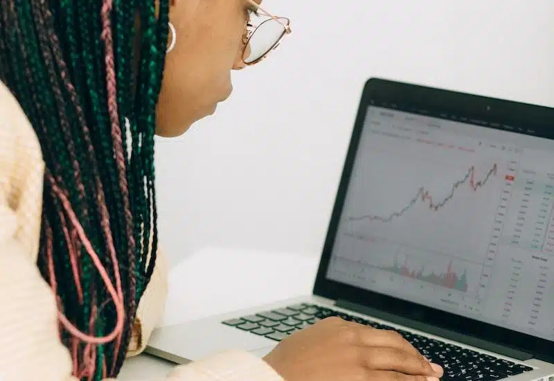 Woman in a Beige Jacket Analyzing the Graph on her Laptop