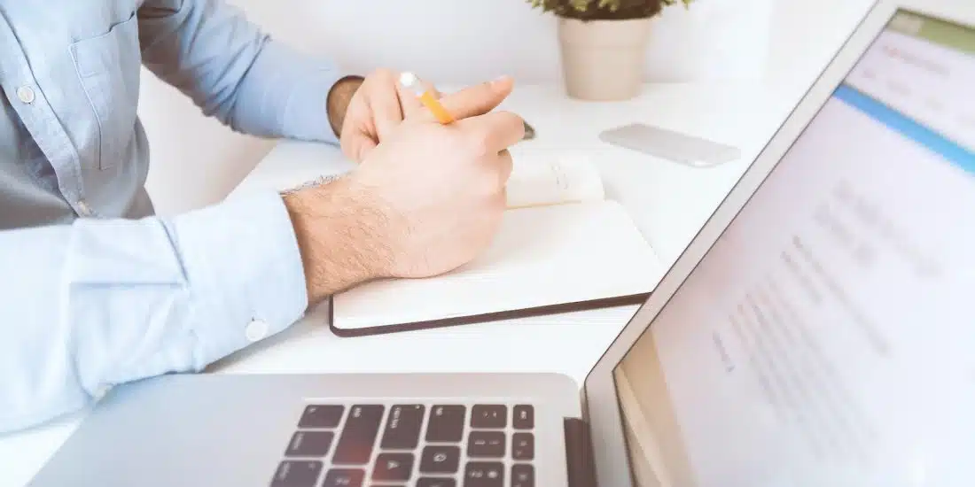 person writing on white notebook