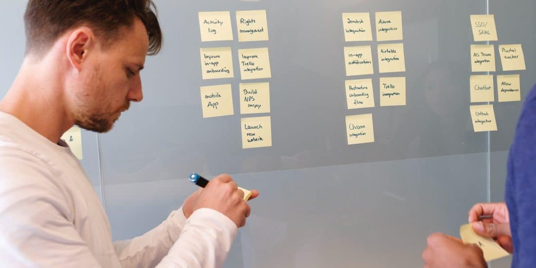 man in white long sleeve shirt writing on white board